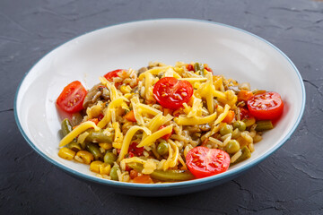 Risotto with mushrooms and cheese and vegetables in a plate on a gray background.