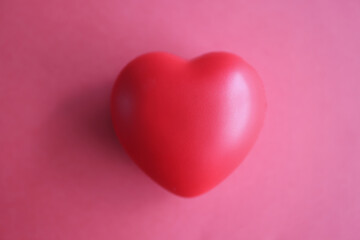 Fototapeta premium Toy rubber heart lying on red background closeup top view