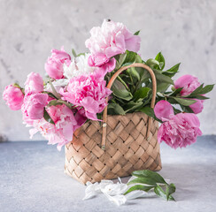 Beautiful peonies in wicker basket on wooden table