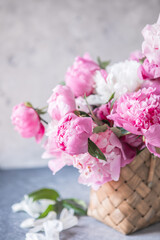 Beautiful peonies in wicker basket on wooden table
