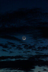 Crescent Moon in dark sky with clouds