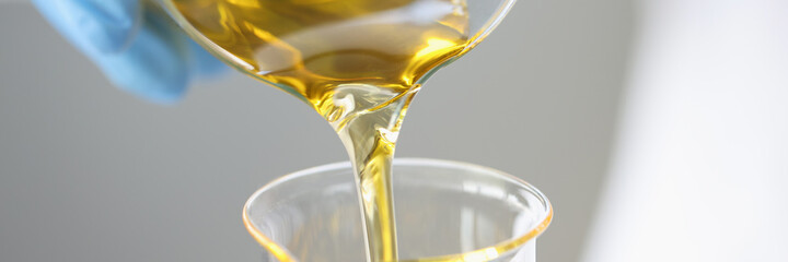 Researcher drains golden liquid into chemical flask