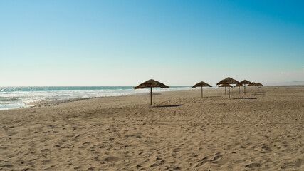 
seashore in the summer sun, beautiful scenery, straw umbrellas