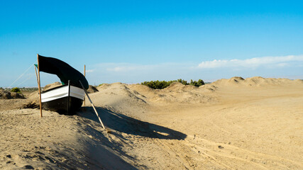 Fototapeta na wymiar old ship in a desert in summer, on sandbar under sun and wind, blue sky and beautiful landscape