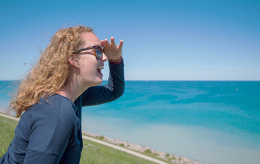 Red Head Girl With Hand Shading Eyes Looking Out Over the Lake Water with Excitement