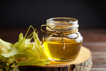 Honey in jar with linden flowers on wooden background