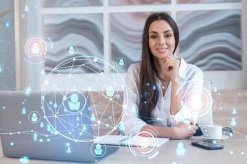 Attractive businesswoman in white shirt at workplace working with laptop to hire new employees for international business consulting. HR, social media hologram icons over office background