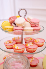 French macaroons on a cake stand .Candy bar with macaron, cakes, cheesecakes, cake pops.Colorful macaroons on serving tray.Decorative sweet birthday table in bright colors of yellow, white and pink.
