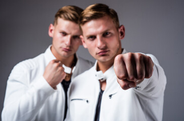 two cousin show fist. young confident brothers. confident fashion models. twins brother in white