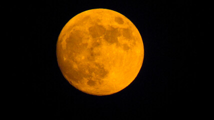 An orange moon surrounded by the darkness of the night
