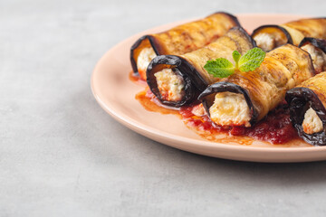 Eggplant rollatini with ricotta, parmesan cheese and tomato sauce. Light background. Copy space.