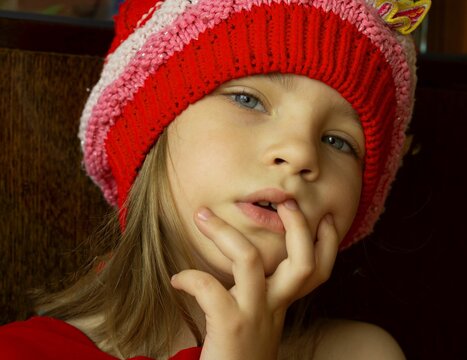 rait of a little Caucasian girl in a knitted hat indoors