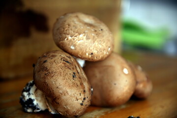 Selective focus of mushrooms, soiled with earth, resting on a wooden surface (Agaricus bisporus)