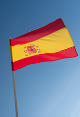 Spanish flag waving in wind. Flag of Spain on blue sky background.