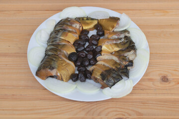 Marinated fish and olives in a white plate close up - Wooden background