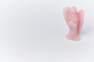 an angel made of rose quartz in the right corner on white background, on the left side copy space for any text