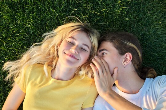 Happy couple of teenagers on green grass