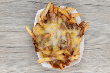 Overhead view of melted cheese smothers this entire boat of chile cheese french fries as a very...