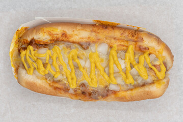 Overhead view of loaded chile cheese hot dog smothered in cheese, chile, and onions.