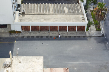 Aerial view of man cleaning sidewalk and street.