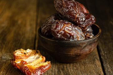 Dried dates in folk ceramic dishes on a wooden background.
