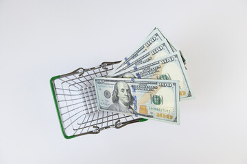100 dollar bills in a mini shopping basket on a white background, top view, flat lay. Finance...