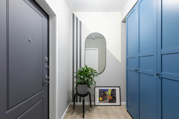 Entrance hallway in a modern design apartment: grey and white walls, built-in wardrobe. Safety home, high-quality front door - obrazy, fototapety, plakaty