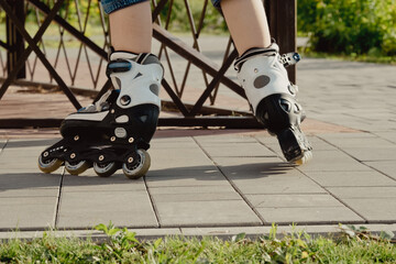 Little boy in protective equipment and rollers stands on walkway in park, low angle view