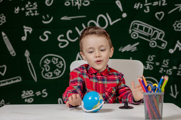 Preschooler boy making school homework. School boy with happy face expression near desk with school supplies. Education. Education first. School concept.