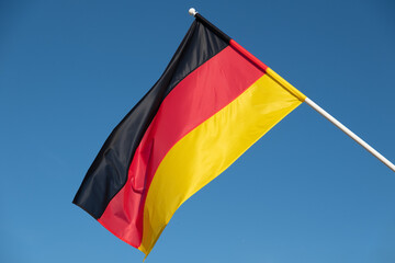 German flag waving in wind. Flag of Germany on blue sky background.