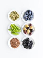 Top down view of small bowls filled with various healthy raw ingredients, against a white background.
