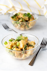 Two bowls of potato salad ready for eating, against a light background.