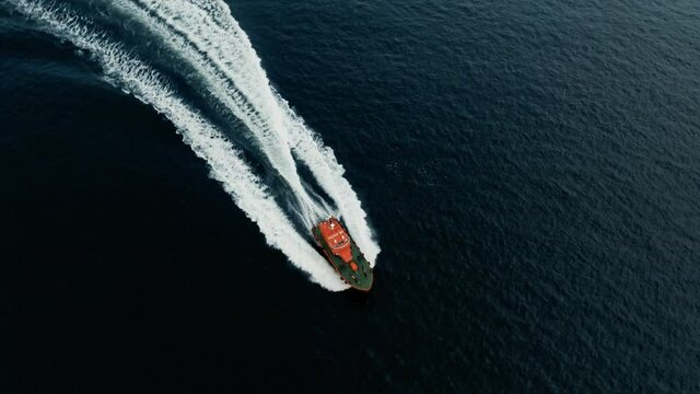 Aerial Drone Cinematic - chasing and circulating bright orange coast guard boat in the ocean right outside of the coast of Helsingborg Sweden and Helsingor Denmark in Oresund