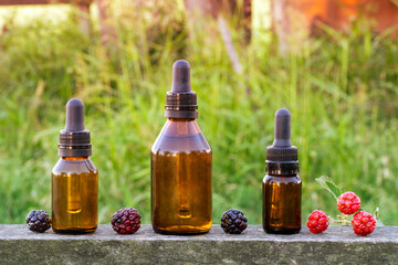 Blackberries essence oil in medicine droppers over an old wood with blurred green background
