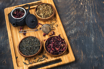assortment of dry tea in wooden bowls and teapot