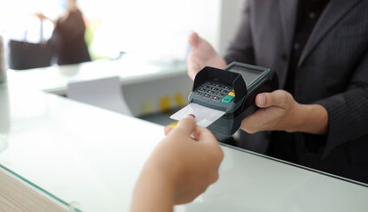 Customer hand swiping credit card through payment terminal for payment.