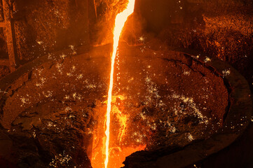 Molten iron flow. Liquid metal is poured into the ladle in a thin stream