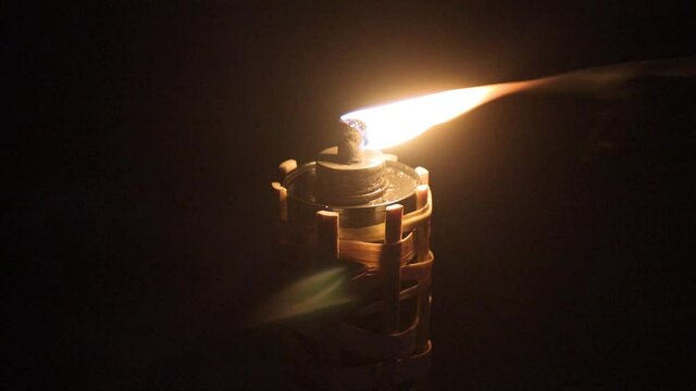 Low light shot of Tiki torch made from bamboo flickering in the wind late in the evening