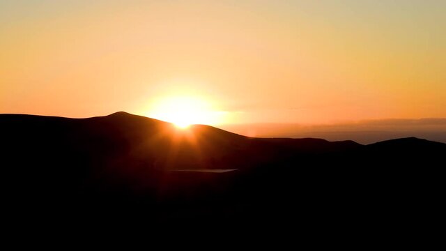 Beautiful panning shot of stunning sunset on horizon with mountain range silhouette. Shot in Fletcher Bay, Coromandel Peninsula, Waikato, North Island, New Zealand
