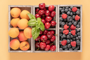 blueberries, cherries and peaches in a wooden box.