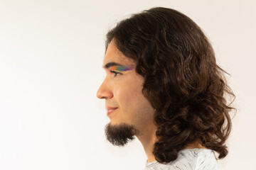 portrait of a gay hispanic man in makeup with a rainbow in his eyes on a white background smiling