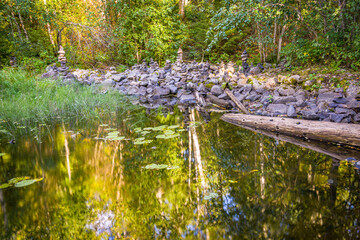 A Suna river overflow just before Kivach waterfall with multiple stone pyramids built by tourists in Karelia, Russia