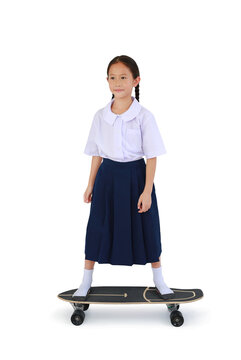 Asian little girl child in Thai school uniform standing on skateboard isolated on white background. Image full length with Clipping path