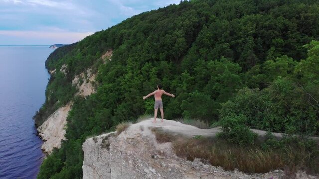Young shirtless man free man running to a cliff and raises his hands apart
