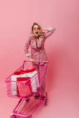 Model in pink outfit carries full of bags with new clothes pink trolley