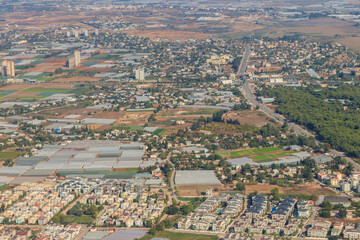Aerial view of Antalya suburb with houses, greenhouses and fields in Turkey. View from a plane
