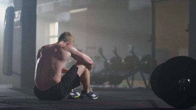 Exhausted young men resting after intensive workout in gym. Fitness healthy man tired after strength training exercise at gym. Tired male fit model with standing and relaxing after intense workout.