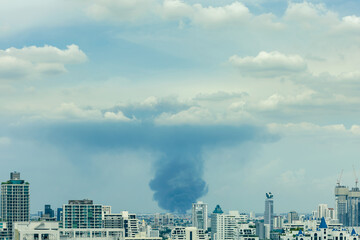 Fototapeta premium huge explosion and fire at plastic factory on outskirts of town, thick black smoke filled sky over city after explosion at chemical manufacturer, environmental pollution concept