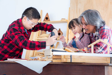 A carpenter uncle is teaching boys and girls to assemble wooden boxes in his carpentry workshop.