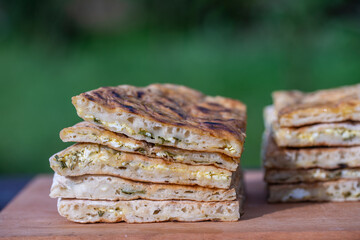 Pieces of baked dough tortilla with cottage cheese and herbs on a wooden table, close up